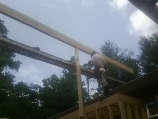 Carpenter setting a ridge beam over a new addition frame — Ice Dam Removal by Roofing Brothers in Irondale
