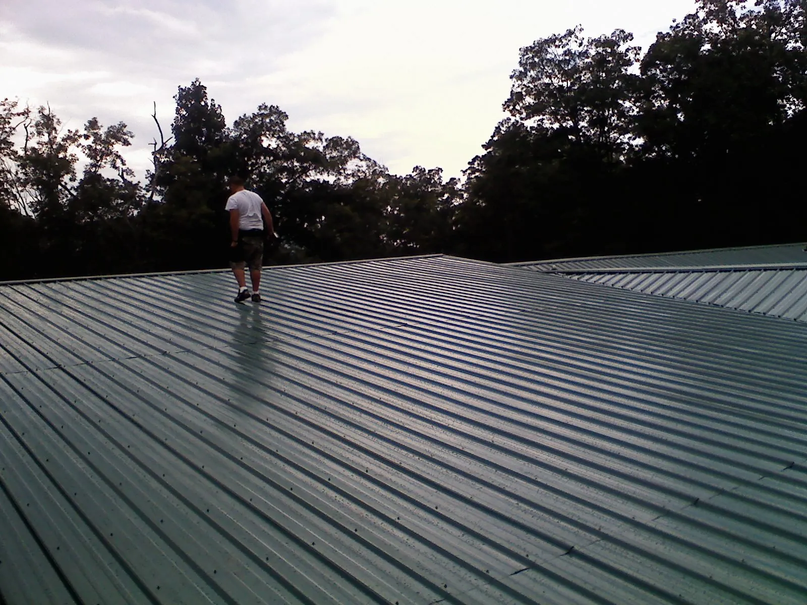 Roofer walking a wide expanse of new green metal roofing in Irondale