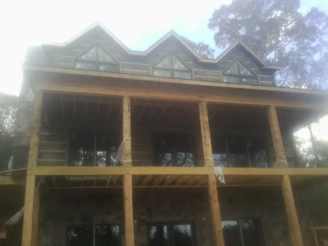 Dormers and porch framing on a large log home under construction — Roof Coating work by our crew in Irondale