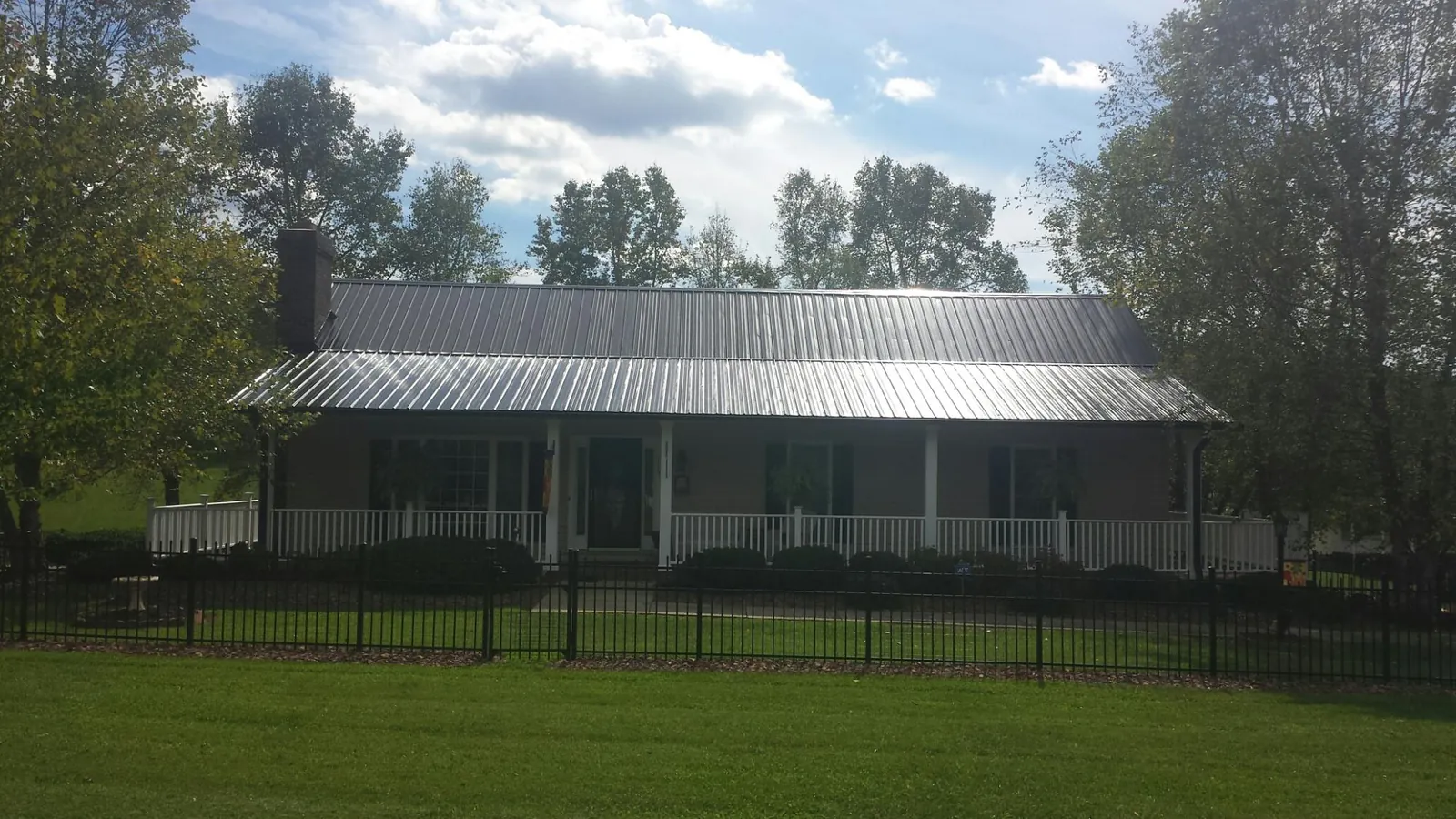 Gray metal roof on a brick ranch with a full width front porch — Gutter Guard Installation work by our crew in Irondale