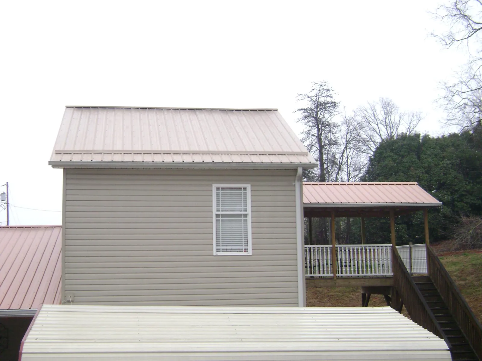 Tan metal roofs on a two story addition and attached porch, from a Roof Replacement job in Irondale