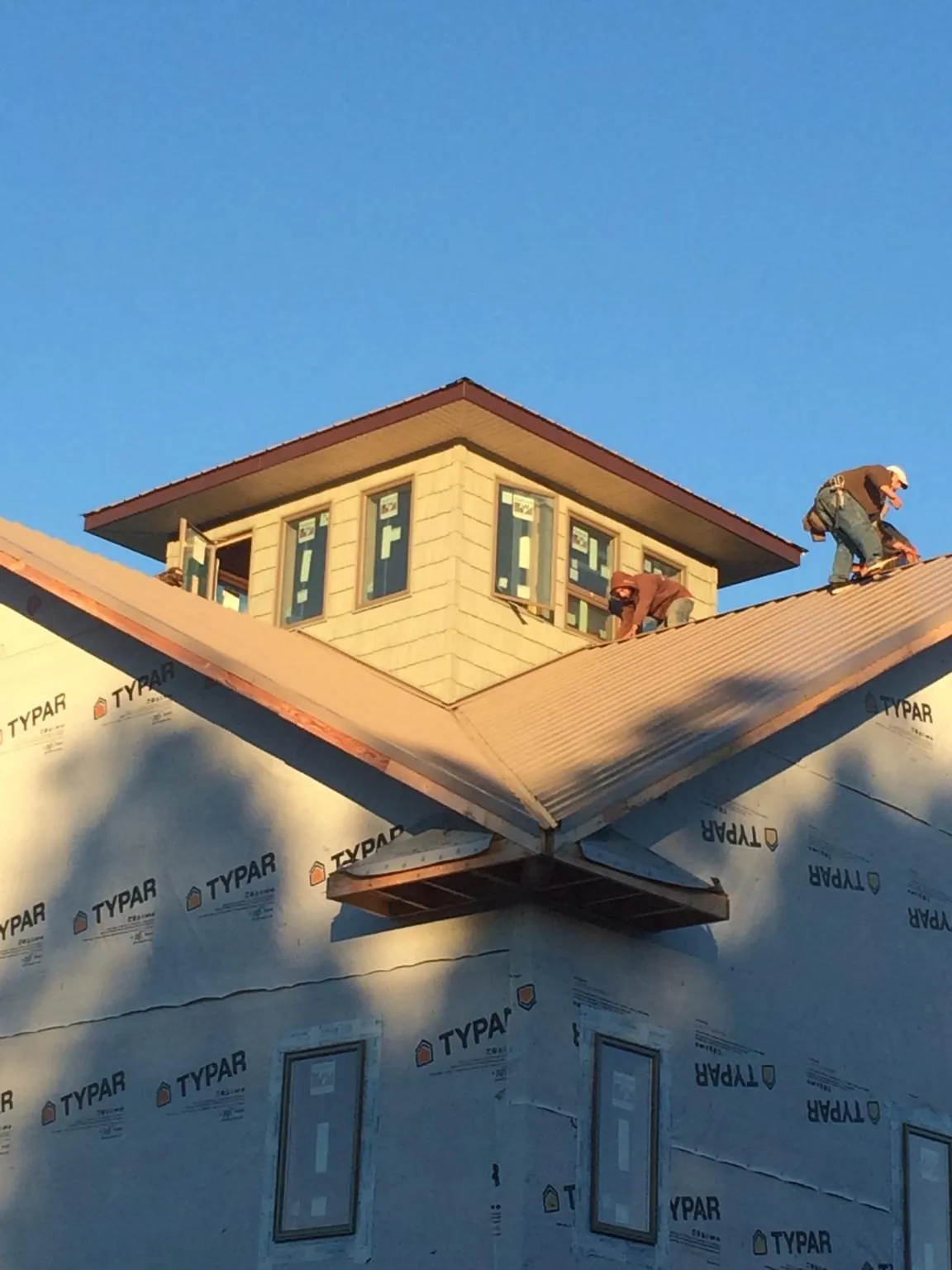 Roofers working around a rooftop cupola on a new metal roof at sunset — Roof Waterproofing in Irondale by Roofing Brothers